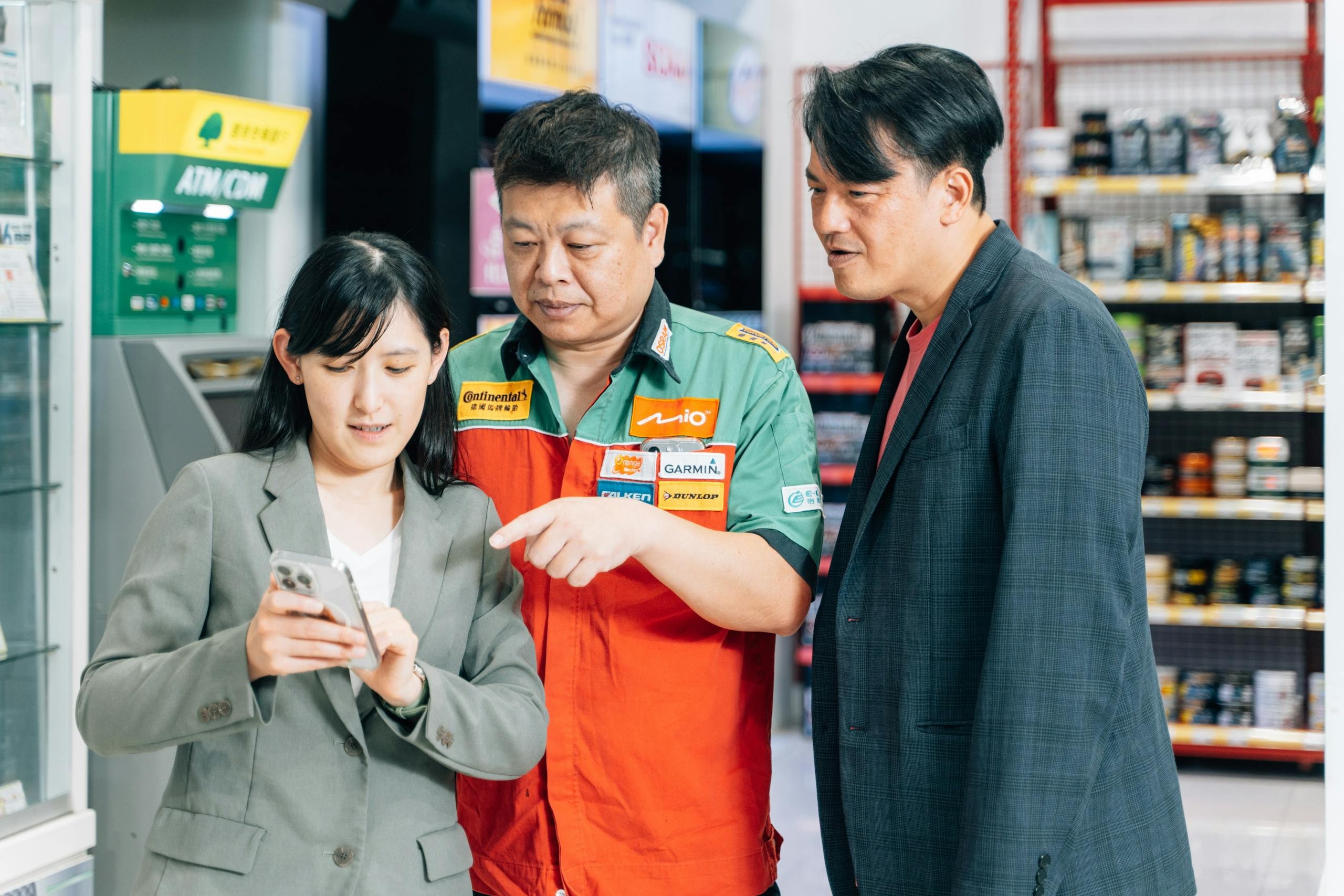 羅文海（中）和徐郁涵（左）、卓星在（右）正在討論手機操作介面的友善程度，期望透過持續的反饋與優化，讓顧客第一次使用就上手。/ Photo Credit：張家瑋